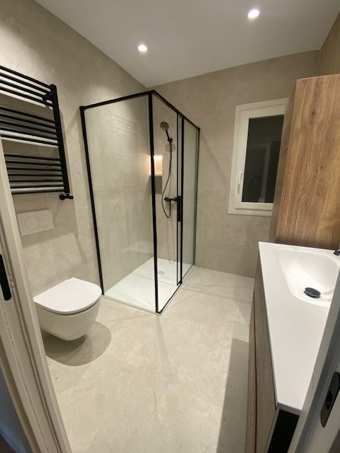 Baño con mampara y radiador toallero negros