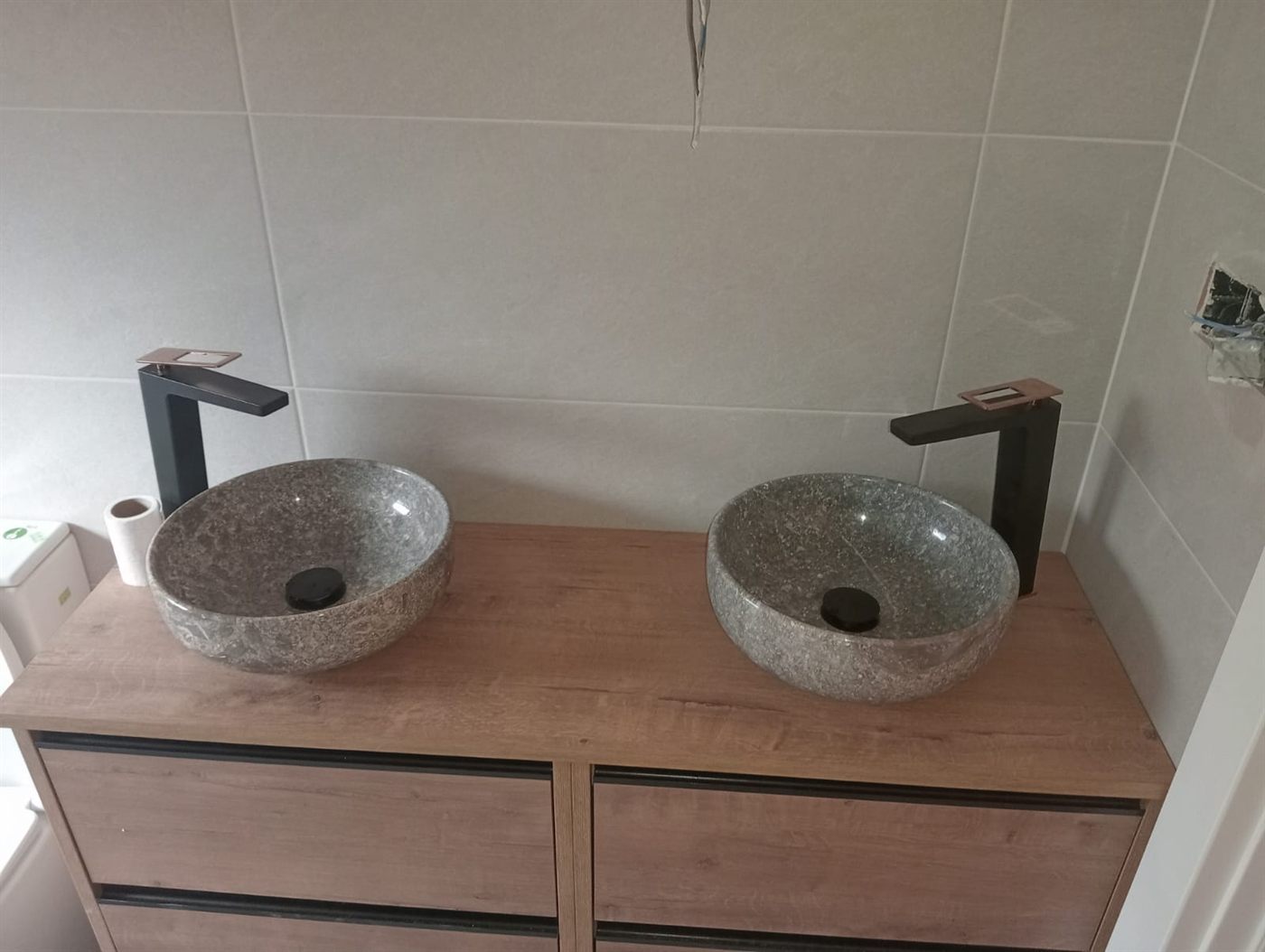 Detalle de dos lavabos de piedra sobre un mueble de madera