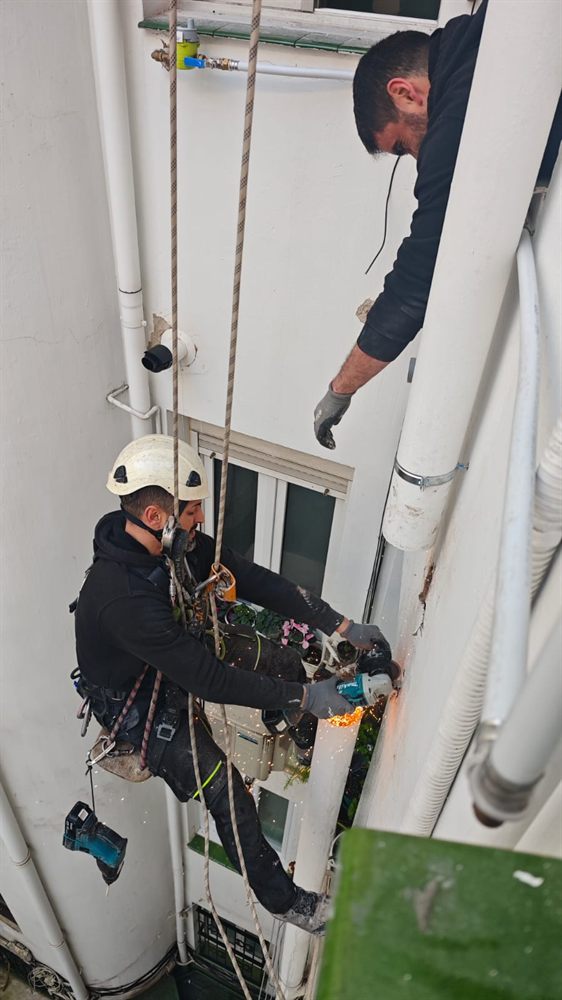 Operario suspendido con arnés trabajando en un patio interior